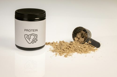 a jar of protein powder next to a scoop of protein powder